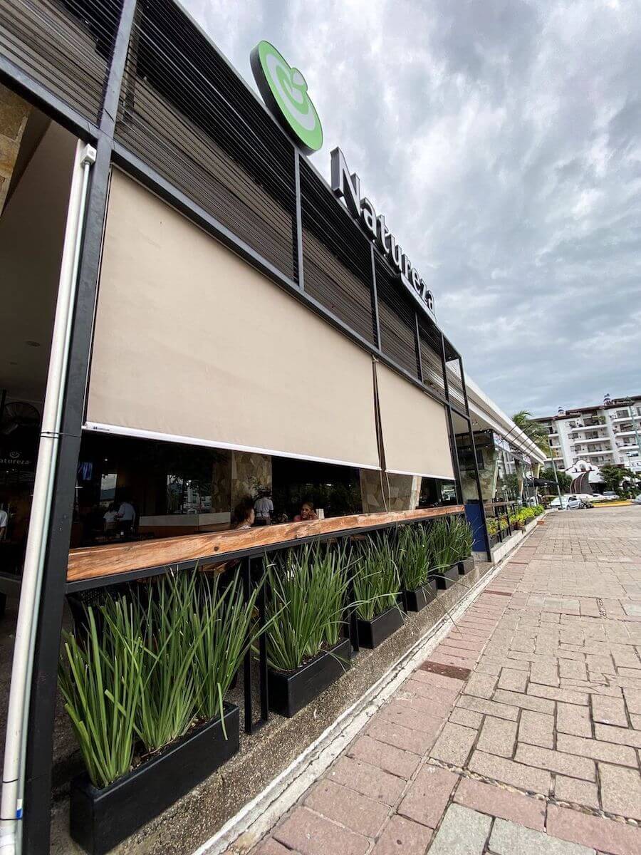 Un restaurante con vista a la Marina de Puerto Vallarta, con plantas, creando un ambiente inolvidable en un entorno natural.