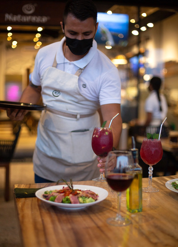 Un mesero está preparando una comida memorable en Natureza Restaurante en Marina Vallarta, Puerto Vallarta.